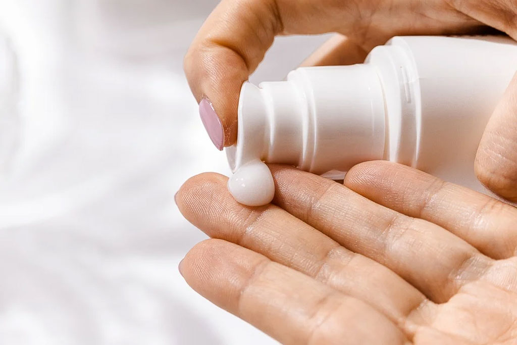 Essential Travel Beauty tips - woman dispenses SPF moisturizer in hand 