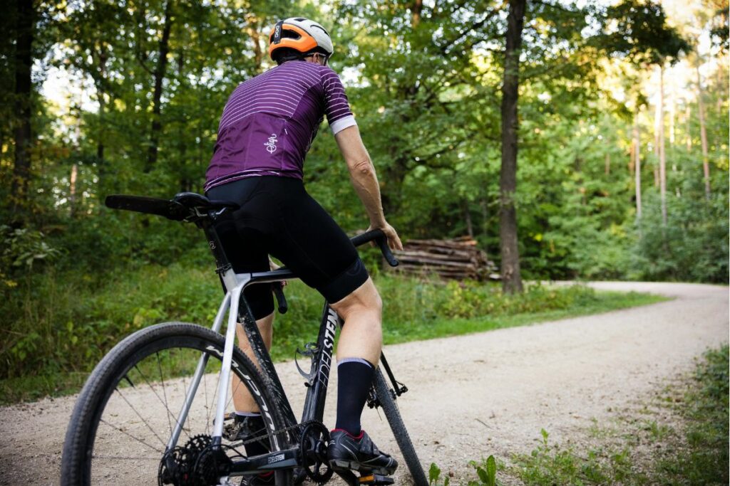 Cyclist riding a gravel bike on a tree-lined path