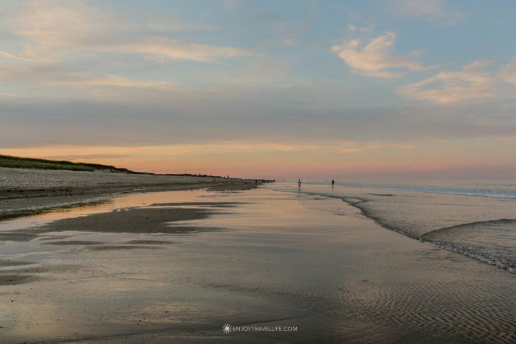 Wide view of Brewster Flats at sunset with rippled sand and shallow water stretching to the horizon on Cape Cod Bay.