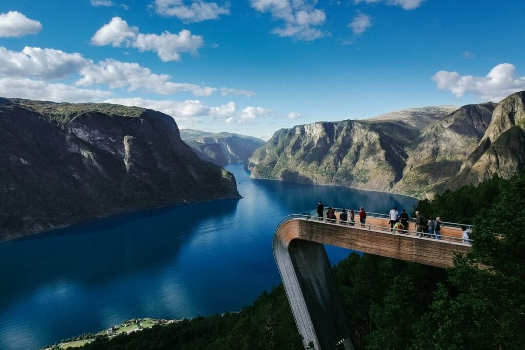 Visitors standing on the Stegastein viewpoint platform overlooking the Aurlandsfjord far below.