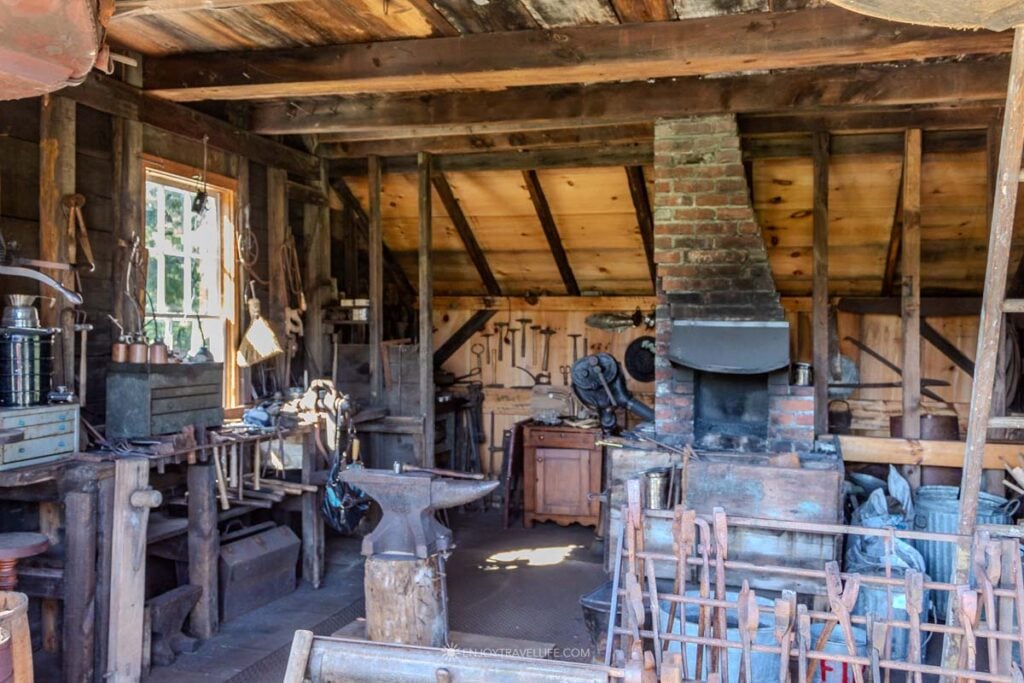 Inside the blacksmith shop at the Brewster Historical Society with anvil, forge, and hand tools on the wall.