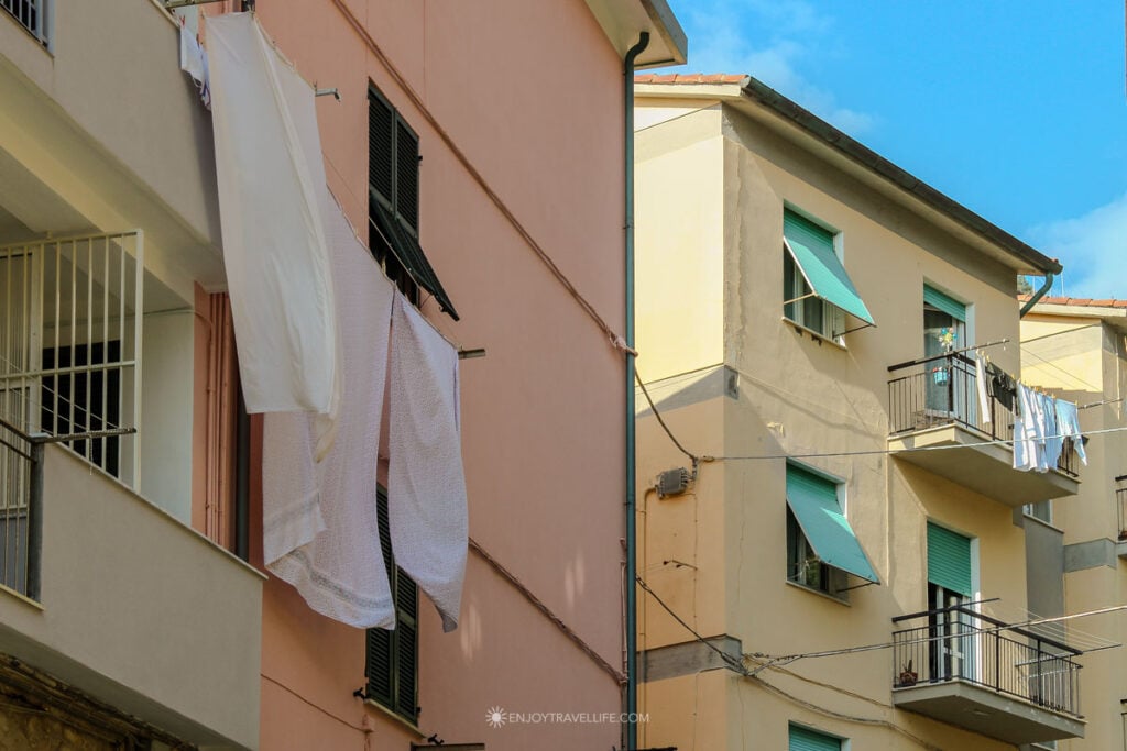 Laundry hanging from pink buildings in Riomaggiore Cinque Terre