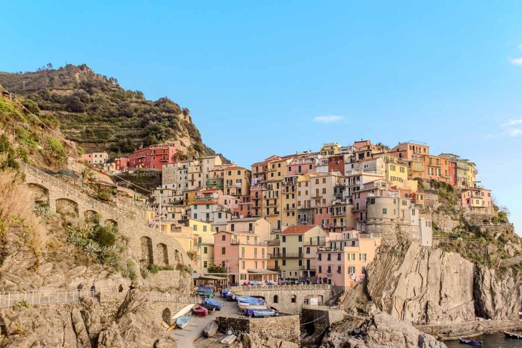 Colorful buildings of Manarola cascading down the clifftop to the small harbor with fishing boats in Cinque Terre Italy.