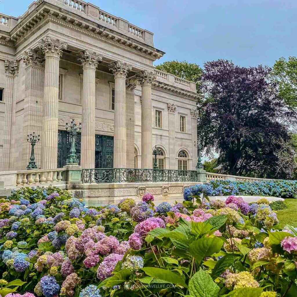 Colorful hydrangeas in pink, blue, and cream blooming in front of the Marble House mansion in Newport, Rhode Island.
