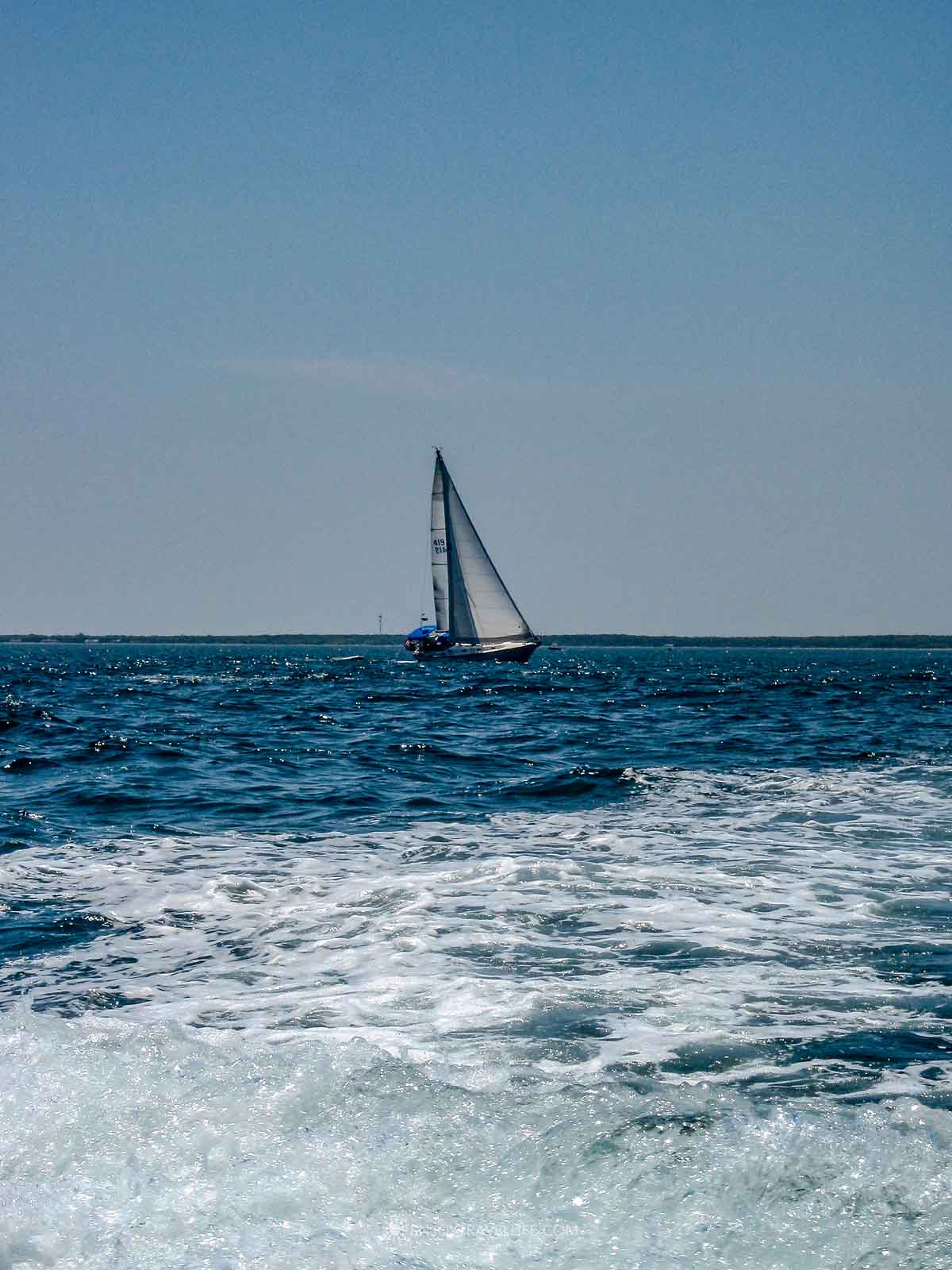 A white sailboat under full sail on the deep blue water of Vineyard Sound