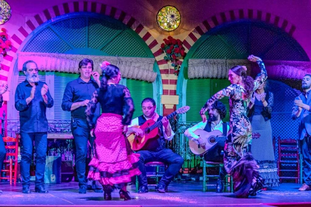 Flamenco dancers in ruffled dresses performing on stage at El Palacio Andaluz in Seville.