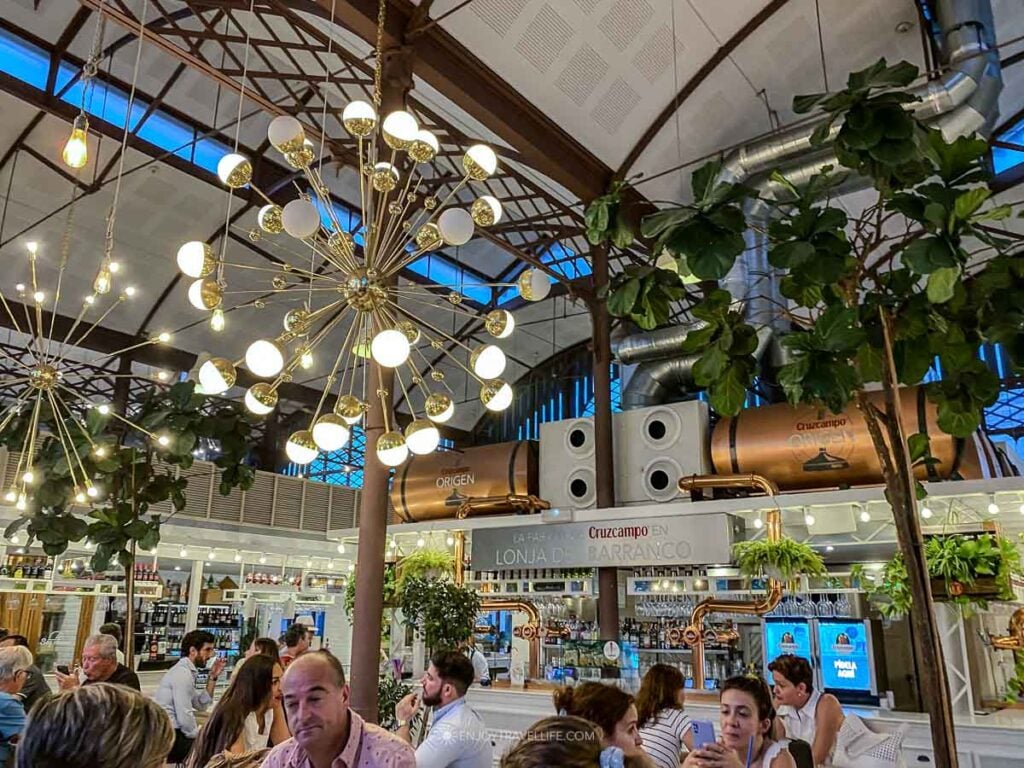 The Mercado Lonja del Barranco gourmet food hall in Seville, set in a riverside iron-and-glass market building.