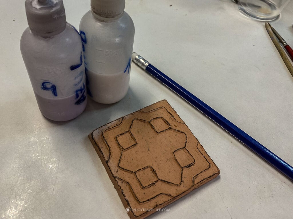 Hand-painting a traditional azulejo tile at a ceramics workshop in Seville's Triana district.