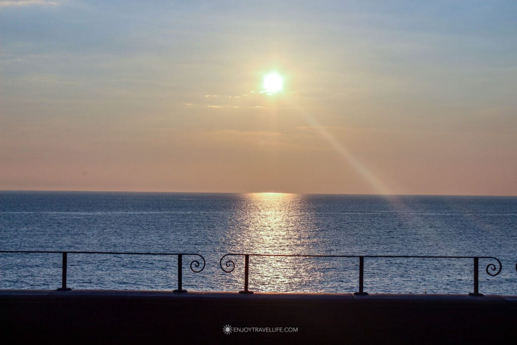 Sunset over the Tyrrhenian Sea seen through a wrought iron railing at the Manarola train station in Cinque Terre.