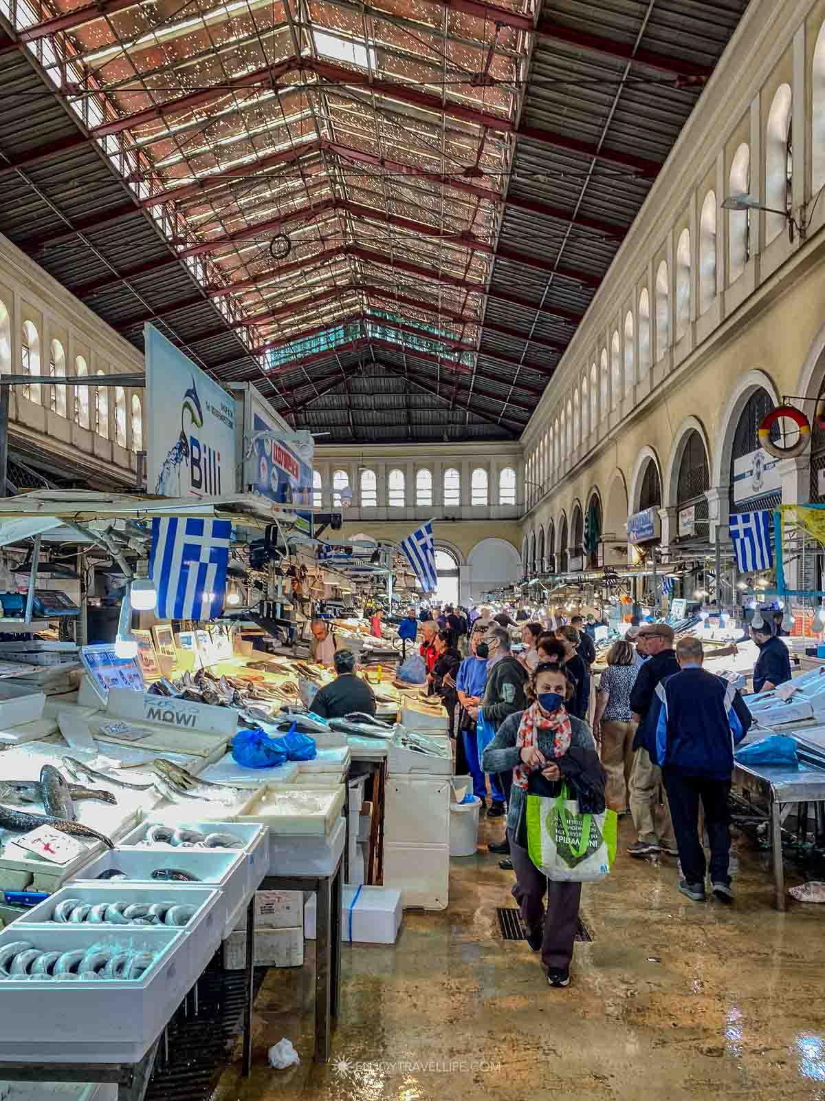 Shoppers move through the historic central market hall in Athens, Greece, during a food tour.