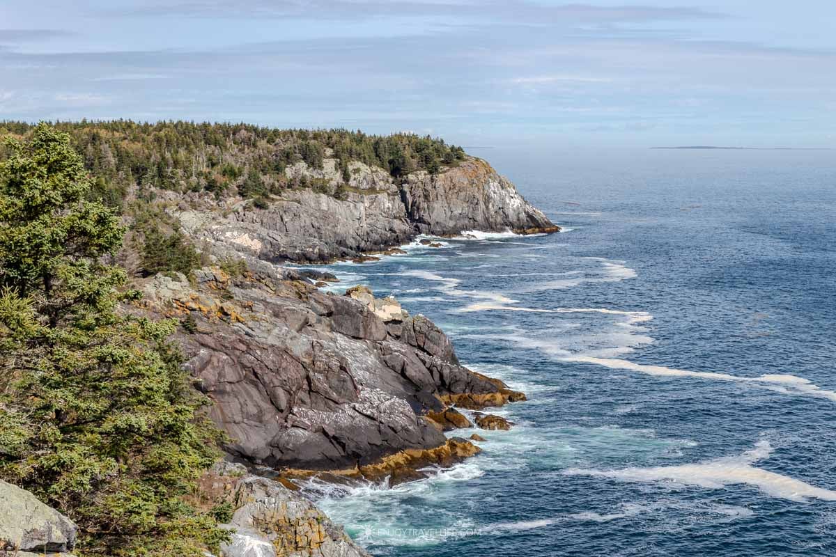 A spruce-covered granite headland juts into the open Atlantic on the far shore of Monhegan Island, Maine.