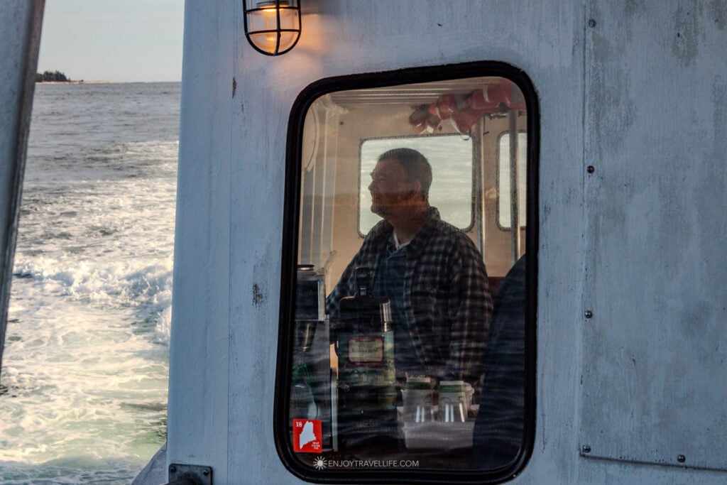 Traveler gazes out from the Balmy Days II ferry during the return trip from Monhegan Island to Boothbay Harbor, with the boat's wake trailing across the water behind him.