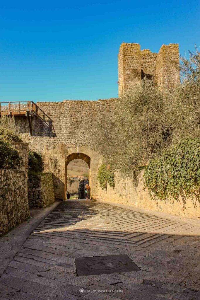 Stone arched gateway and fortress walls with a tower at Monteriggioni in Tuscany.