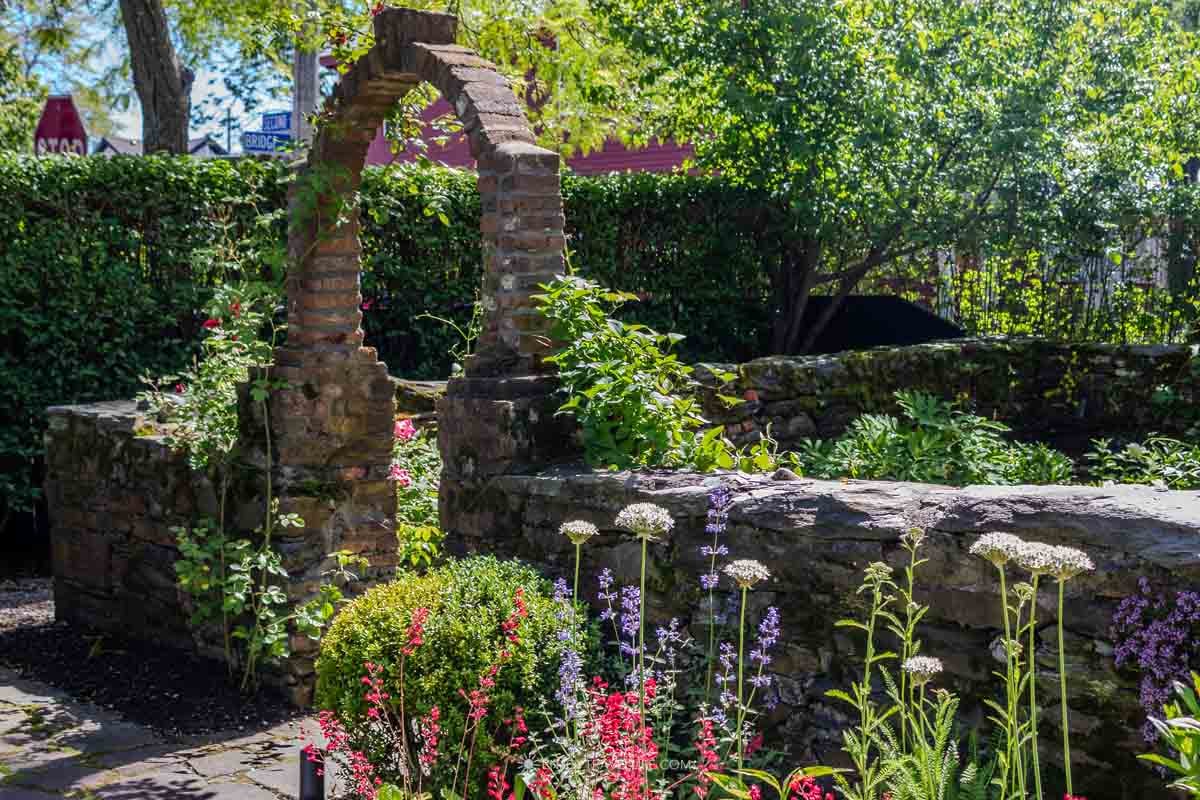A stone arch frames a blooming private garden on Newport's Secret Garden Tour.