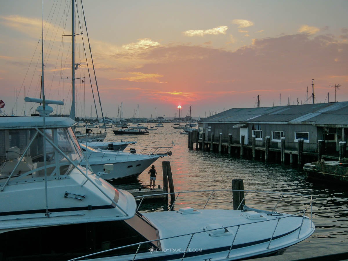A classic sailboat glides past Fort Adams at sunset in Newport, Rhode Island.