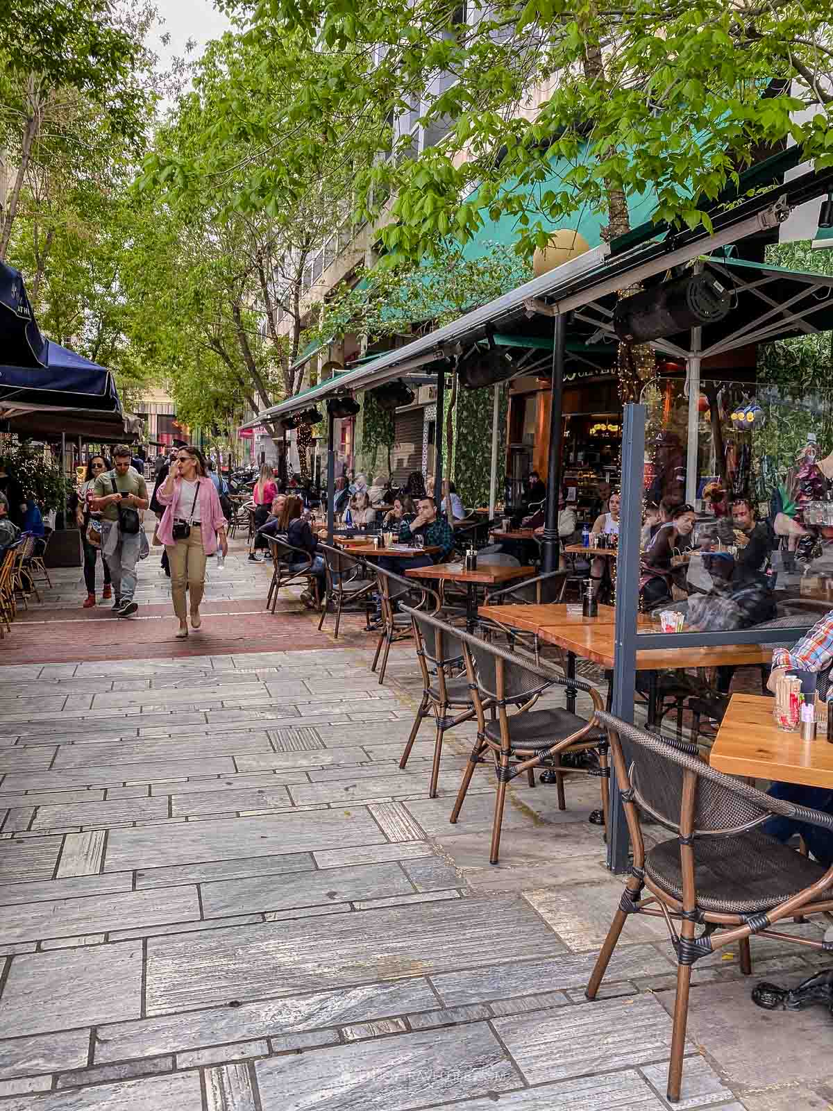 A narrow Plaka street is lined with tavernas and cafe tables in central Athens, Greece.