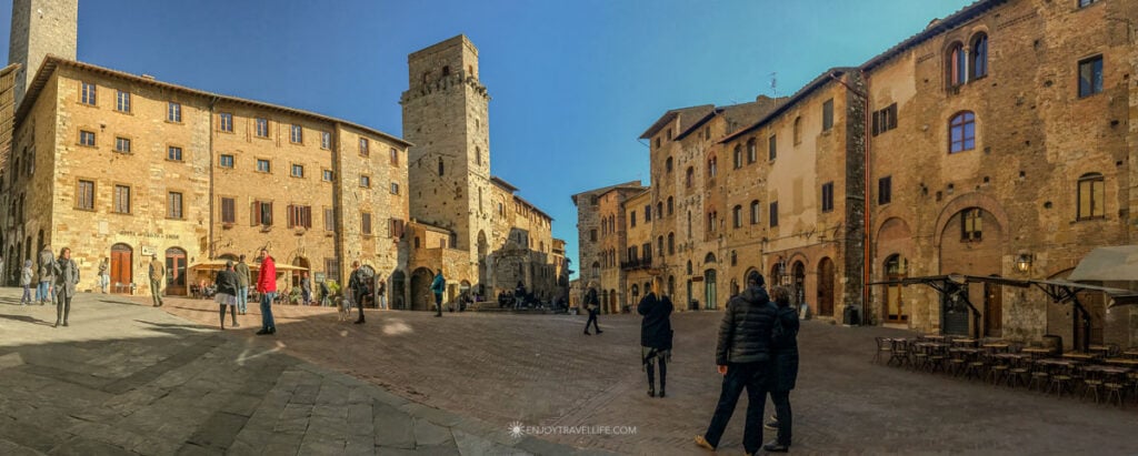 Piazza della Cisterna in San Gimignano with medieval towers and the ancient stone well at its center.