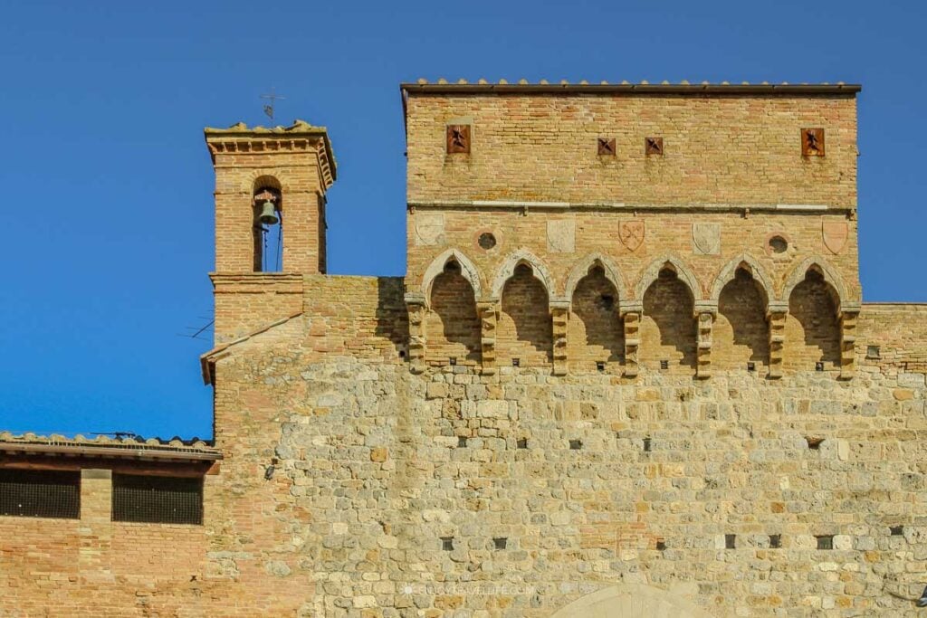 Medieval tower with heraldic crests and pointed arches along the town walls of San Gimignano in Tuscany.