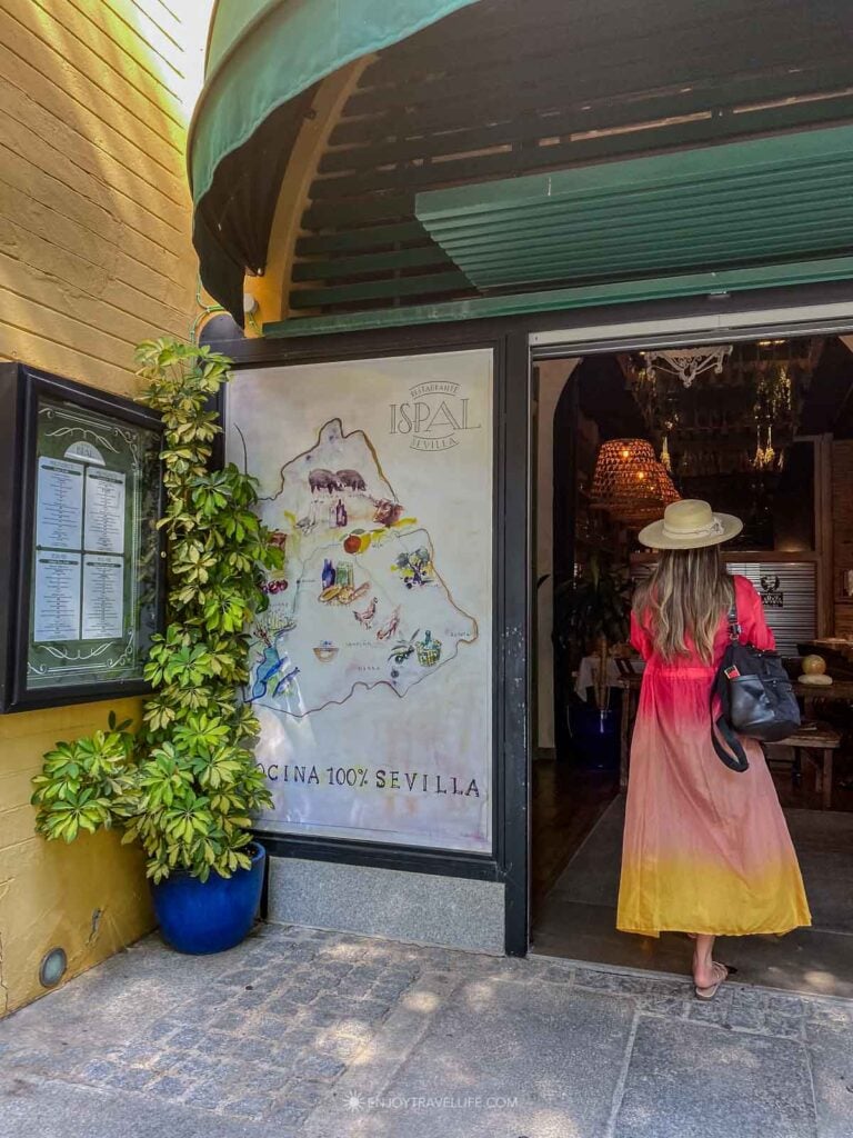 A guest in a brightly colored dress stepping into Restaurante Ispal in Seville.