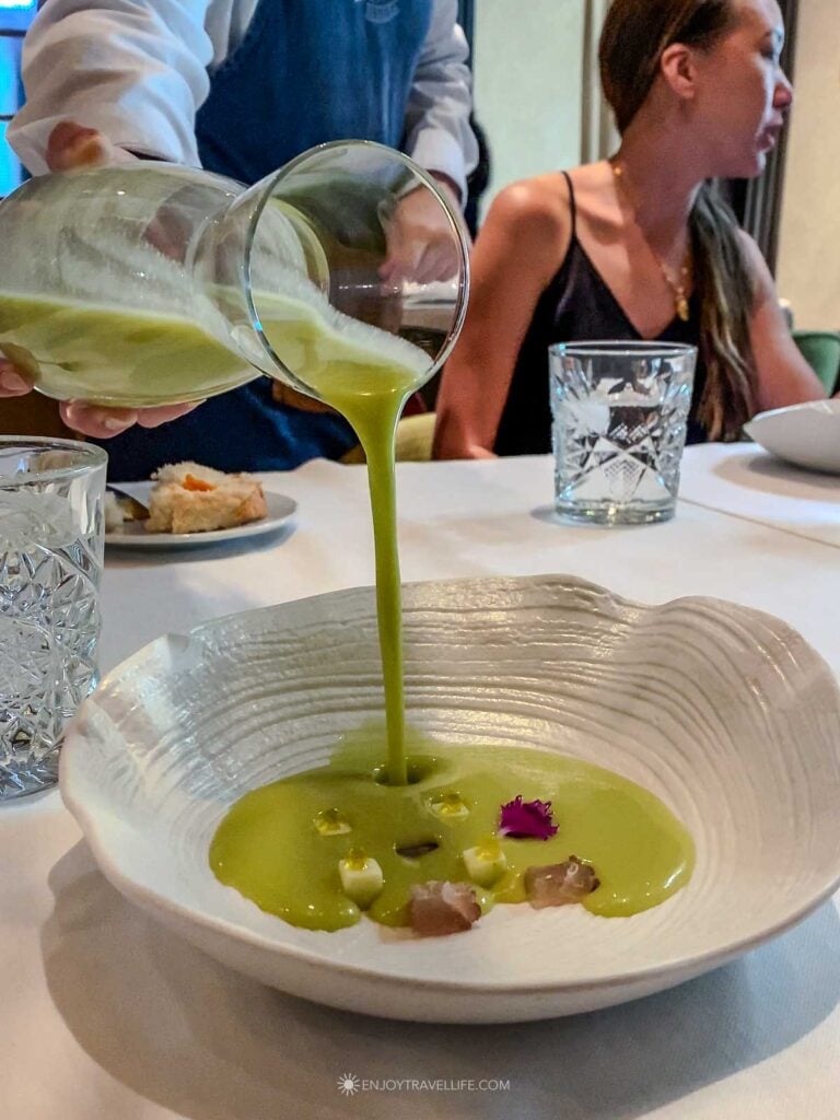 A green gazpacho being poured over garnishes at Restaurante Ispal in Seville.