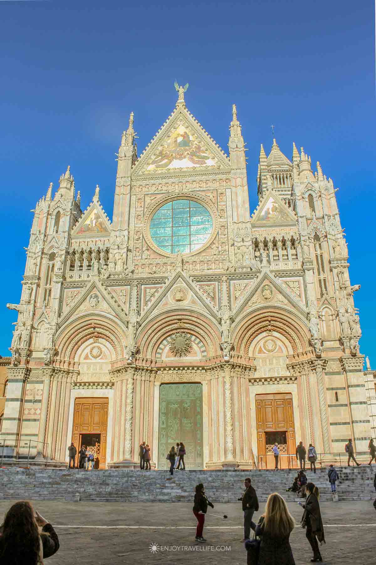 The ornate Gothic facade of the Siena Cathedral Duomo with striped marble and golden mosaics