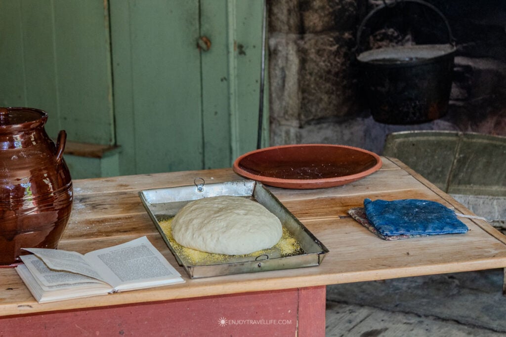 Bread dough rises on a worktable beside the open hearth.