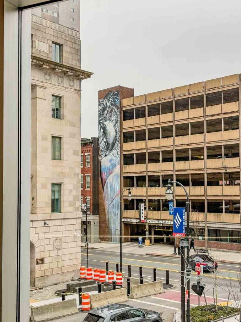 Mural on a downtown building seen through the arched window of the Hanover Theatre in Worcester.