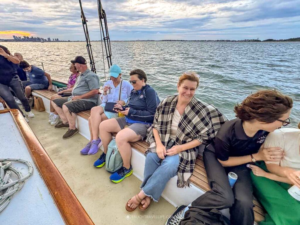Jackie Gately sits at the rail of a schooner in Boston Harbor among other guests on an evening sail.