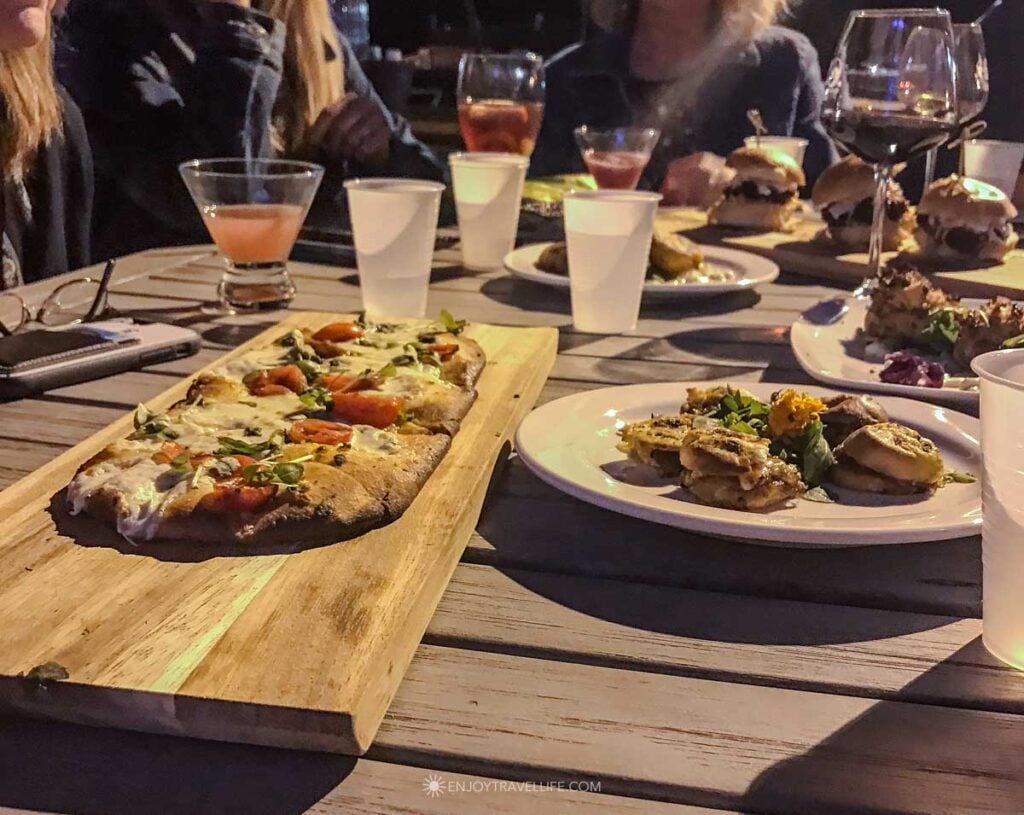 Flatbread pizza and small plates fill an outdoor table at a Village Landing restaurant in Plymouth.
