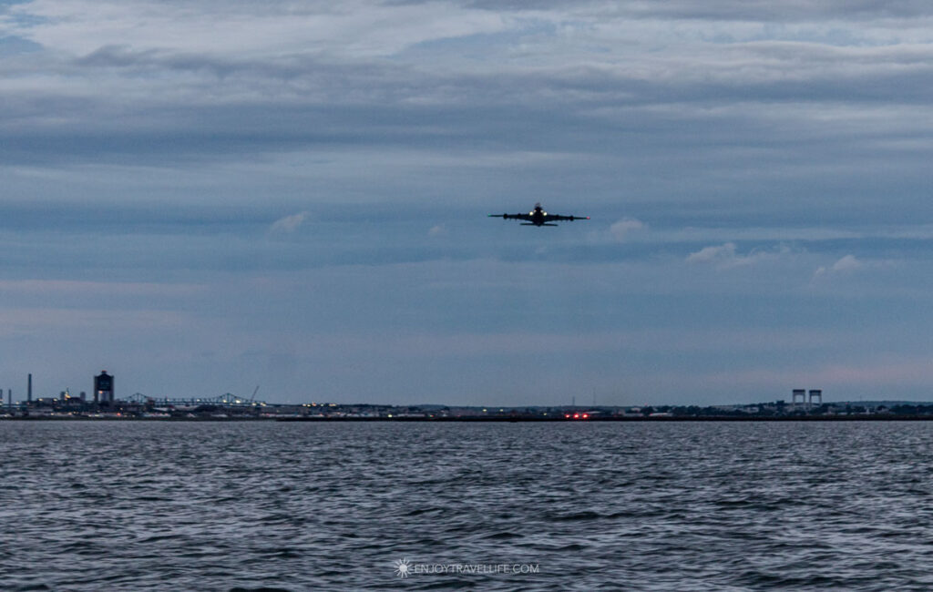 A jet lifts off from Logan Airport, seen low over the water from a schooner in Boston Harbor.