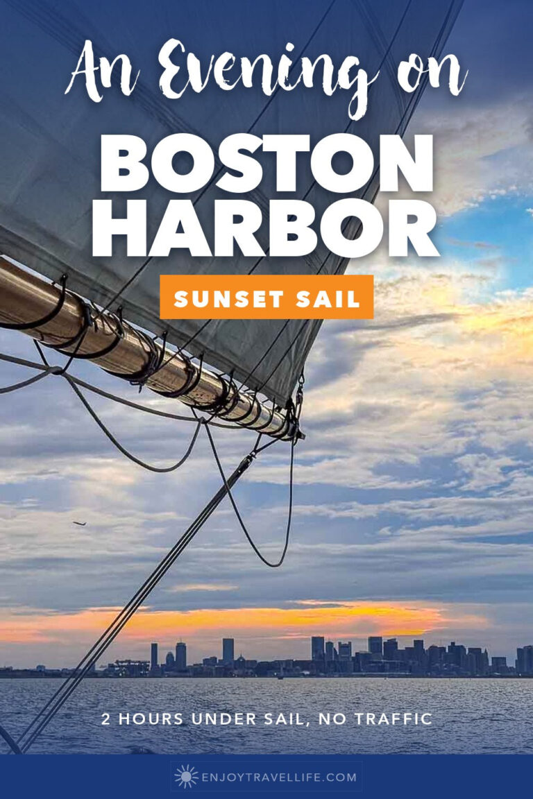 The Boston skyline at sunset seen from under the sails of a schooner on Boston Harbor.