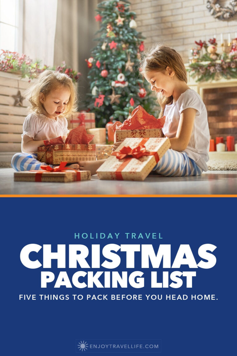 Two children unwrap presents beside a Christmas tree.