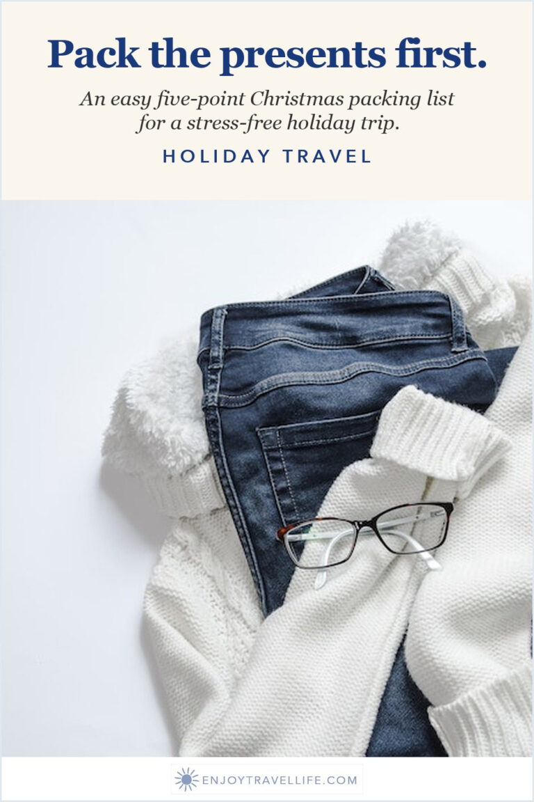 A folded white sweater, jeans and glasses laid out for packing.