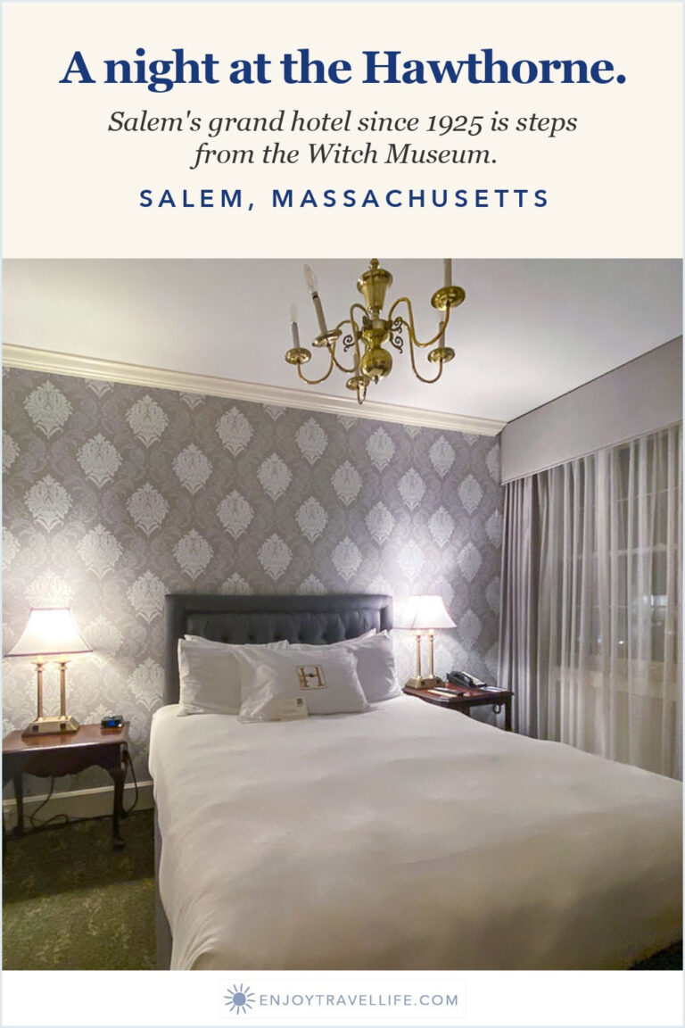 A guest room at the Hawthorne Hotel in Salem, Massachusetts with patterned wallpaper and a white bed.