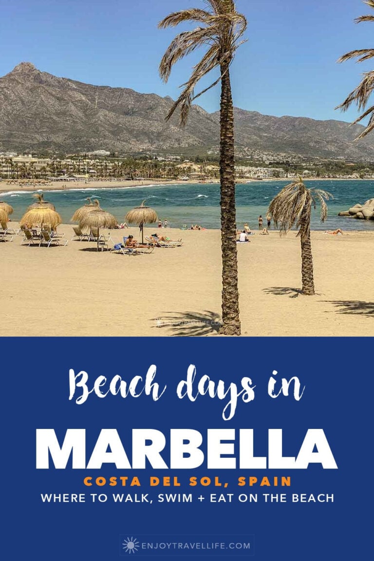 Palm trees and thatched umbrellas on the beach at Marbella, Spain, with La Concha mountain behind.
