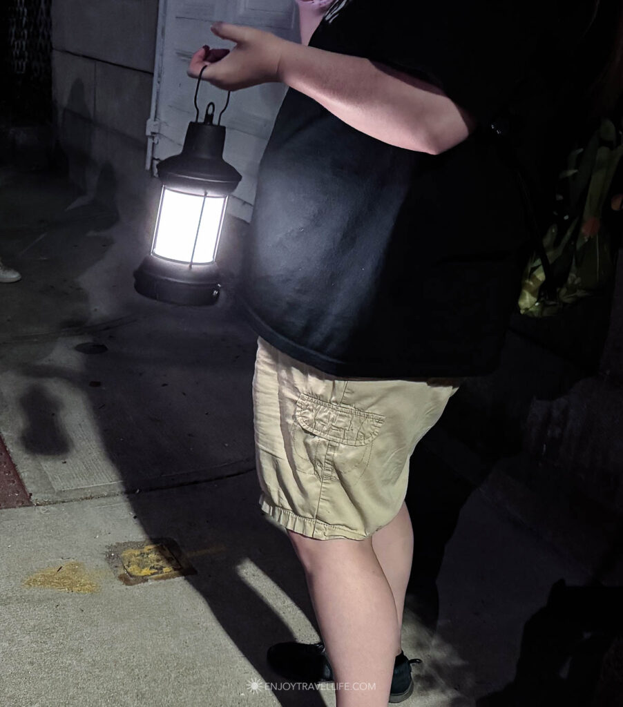 A guest carries a lit lantern along a dark street in Plymouth, Massachusetts.