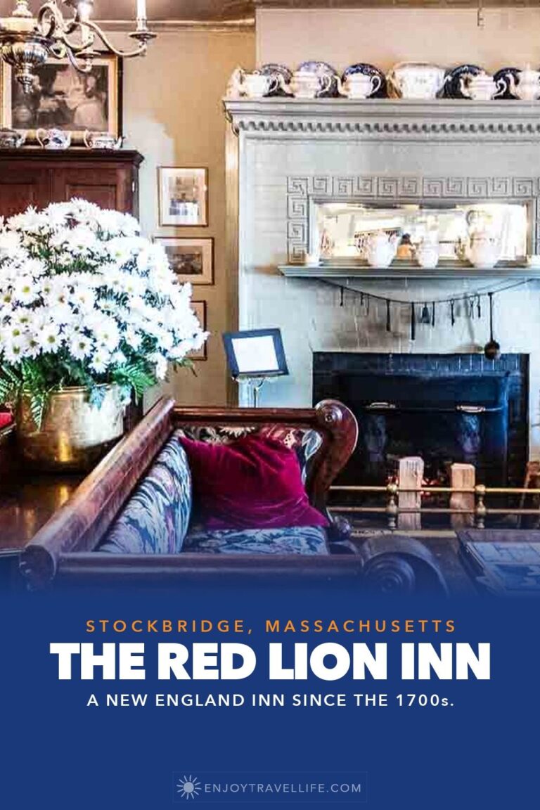 The parlor at the Red Lion Inn in Stockbridge, Massachusetts, with a fireplace, antique settee and a vase of white flowers.