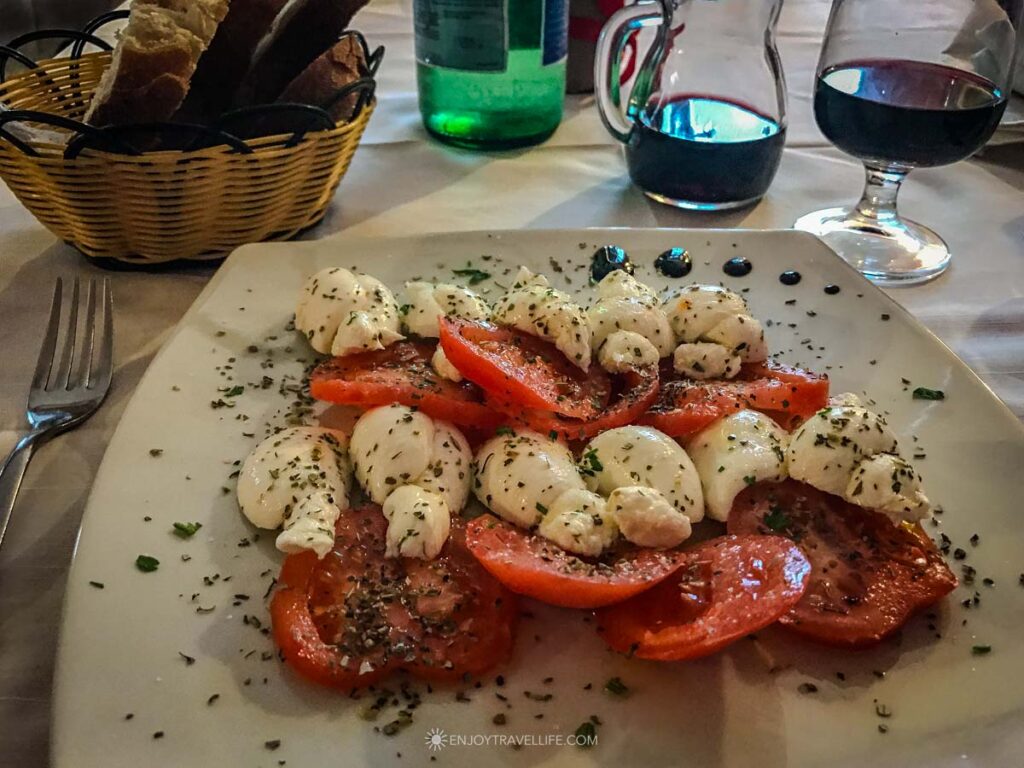 A caprese of sliced tomatoes and fresh mozzarella is served with bread and house wine at Agriturismo Tre Colle in Ariano Irpino, Italy.