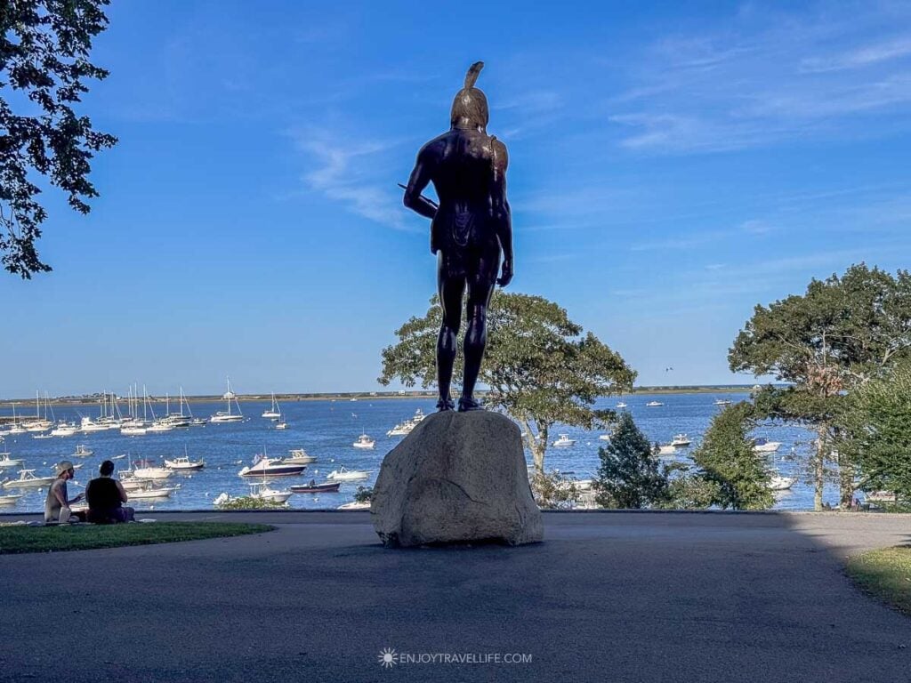 A bronze statue of Massasoit on Cole's Hill looks out over boats moored in Plymouth Harbor.