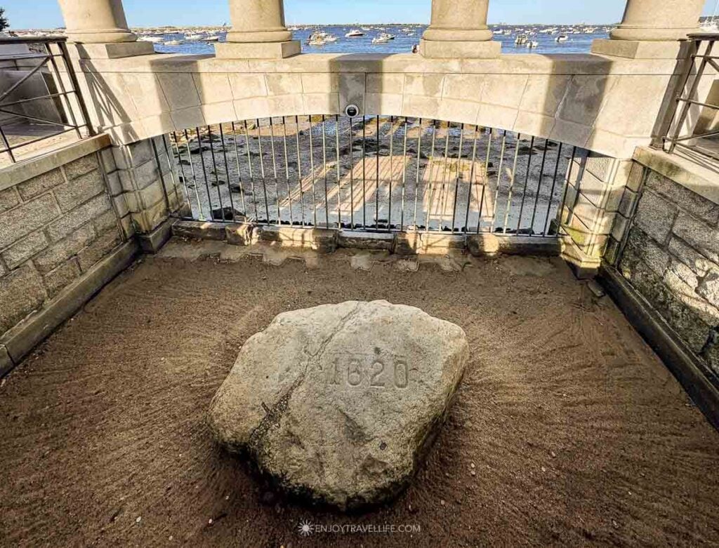 Plymouth Rock, carved with the date 1620, lies in sand beneath its granite portico in Plymouth, Massachusetts.