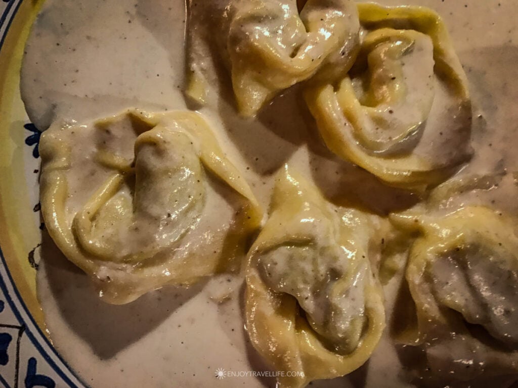 Large tortelloni in a walnut cream sauce fill a hand-painted plate at a trattoria in the Oltrarno neighborhood of Florence, Italy.